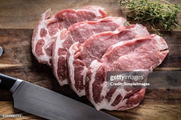 chopped pieces of pork neck on a cutting board with thyme, herbs to flavor the meat. - gegrilltes schweinefleisch stock-fotos und bilder