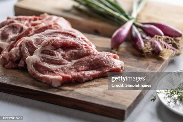 chopped pieces of pork neck on a cutting board with thyme, herbs to flavor the meat. - pork shoulder stock pictures, royalty-free photos & images