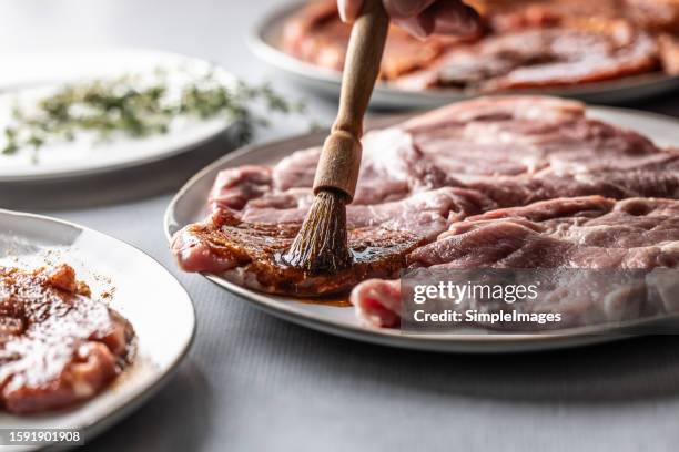 marinating the barbeque meat with a marinade brush - marinated stock pictures, royalty-free photos & images