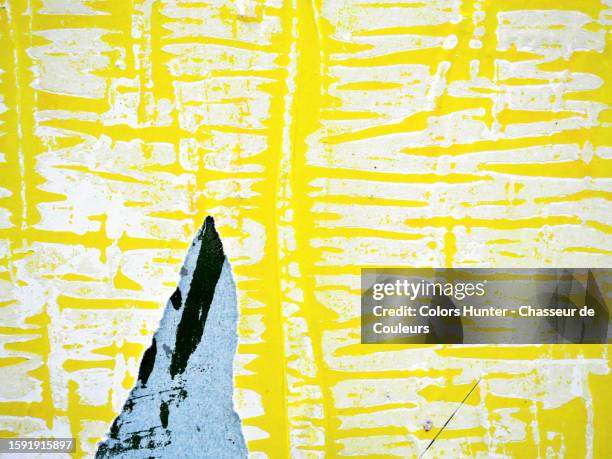 close-up of yellow and blue posters stuck and torn on a wall with traces of white paper in paris, france - ripped newspaper stock pictures, royalty-free photos & images