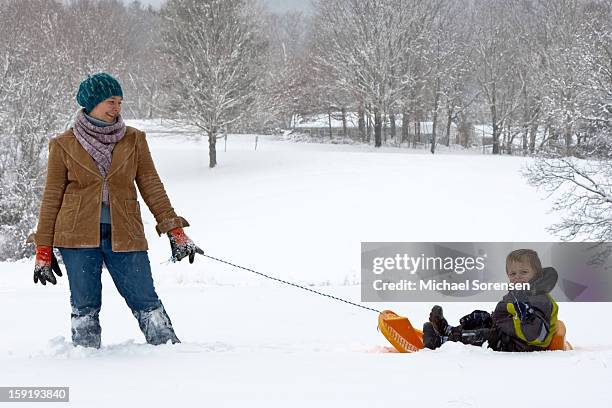 mom pulls son on sled - michael virtue stock pictures, royalty-free photos & images