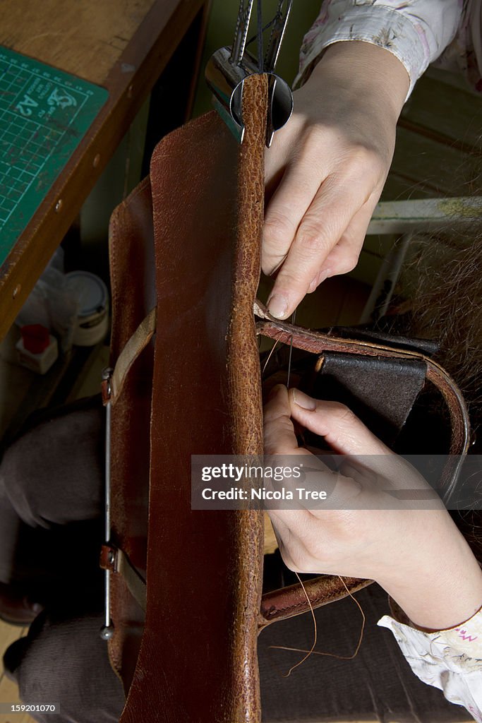 Leather stitcher fixing a satchel