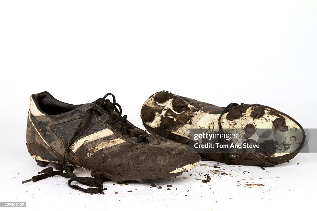 Muddy football boots on a white background