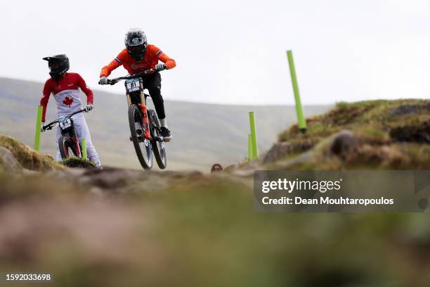 Anthony Poulson of Canada standing while Ike Klaassen of The Netherlands jumps during the mountain bike downhill qualification of men elite in the...