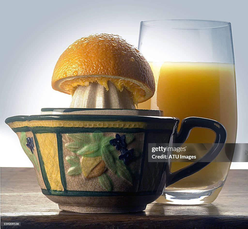 Orange juice and orange half on a squeezer