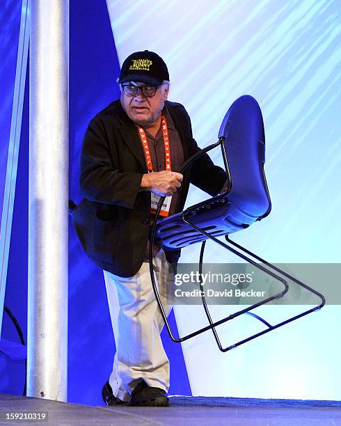 Actor/director Danny DeVito carries his own chair as he arrives to speak at the Panasonic booth during the 2013 International CES at the Las Vegas...