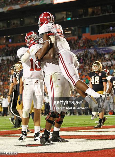 Cyrus Kouandjio of the Alabama Crimson Tide lifts Amari Cooper after Cooper scored a third-quarter touchdown on a 34-yard pass against the Notre Dame...