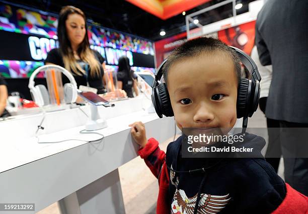 Young attendee listens to music on a pair of JBL J88i headphones at the Harman-Kardon booth at the 2013 International CES at the Las Vegas Convention...