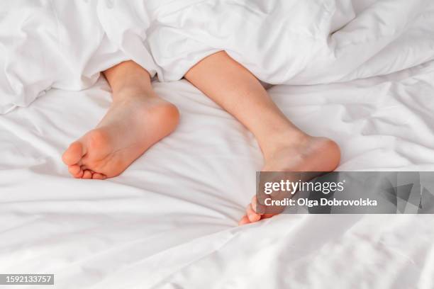 boy's bare feet peeking out from a duvet on a bed - sole of foot stock pictures, royalty-free photos & images