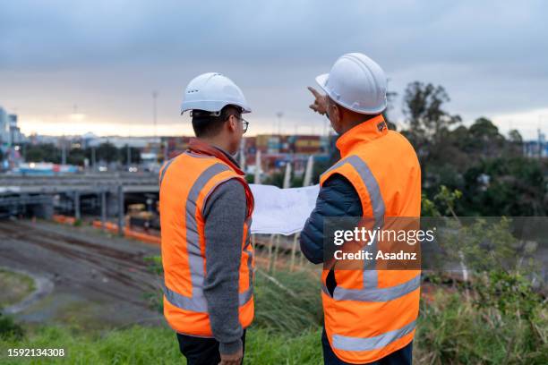 ingenieros civiles que tienen un documento que tiene una discusión sobre el proyecto en curso - civil engineering fotografías e imágenes de stock