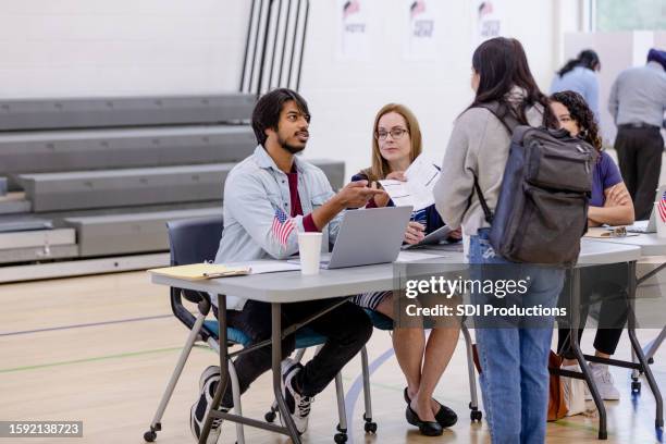 diverse polling place volunteers help voters with ballots - bi partisan stock pictures, royalty-free photos & images