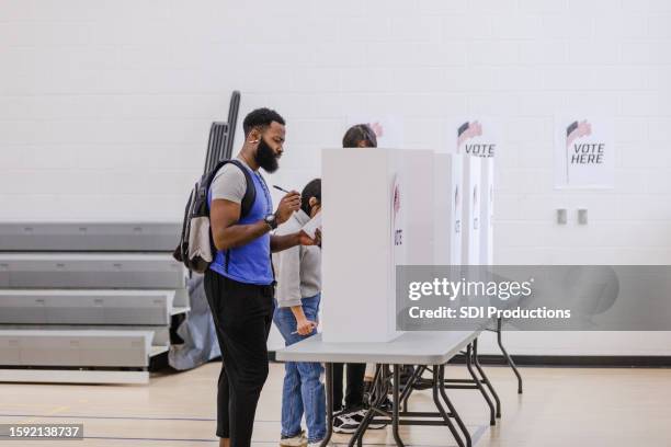 young male college student thinks about his choices while voting - bi partisan stock pictures, royalty-free photos & images