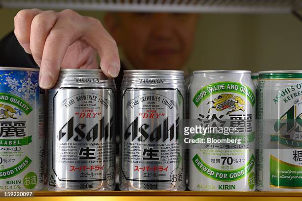 Liquor shop owner stocks cans of Asahi Breweries Ltd. Asahi Super Dry beer in Kawasaki, Kanagawa Prefecture, Japan, on Wednesday, Jan. 9, 2013....