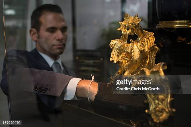 Mikael Kraemer dusts around a pair of dragon chased and gild bronze fire dogs from circa 1720 on display January 9, 2013 at Marina Bay Sands in...