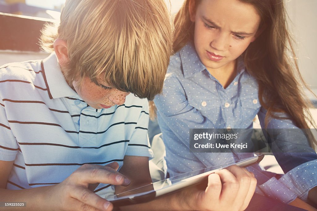 Boy and girl (8 -10) playing with digital tablet