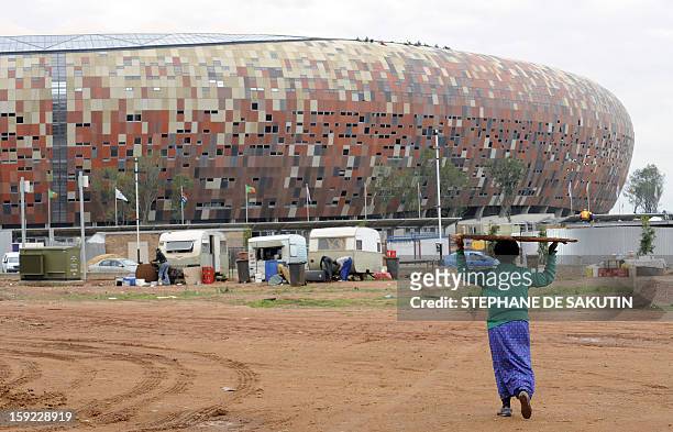 Workers complete the Soccer City Stadium on November 19, 2009 in Johannesburg during a flag-raising ceremony to welcome the 32 countries qualified to...