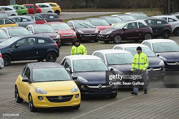 Worker walk past finished Opel Adam cars at a factory parking lot shortly after a celebration to mark the launch of the new Opel compact car at the...