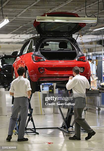 Worker attach spoliers to Opel Adam car next to the assembly line shortly after a celebration to mark the launch of the new Opel compact car at the...