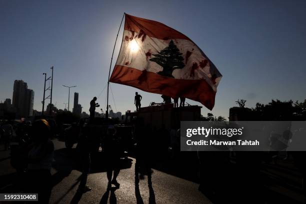 Protesters lift the Lebanese flag on the third anniversary of August 4 Beirut blast on August 4, 2023 in Beirut, Lebanon. Amid a declining economic...