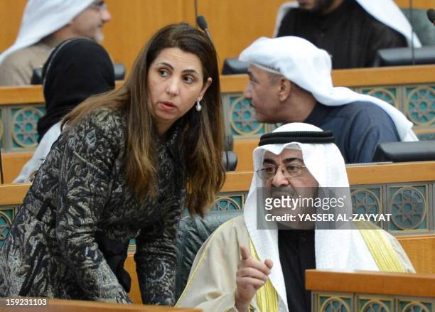 Kuwait's Interior Minister Sheikh Ahmad al-Hmoud al-Sabah talks with Minister of Planning and Development Rola Dashti during a parliament session at...