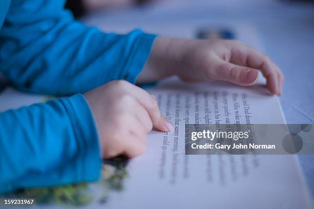 close up boys fingers pointing to words in book - child reading a book stockfoto's en -beelden