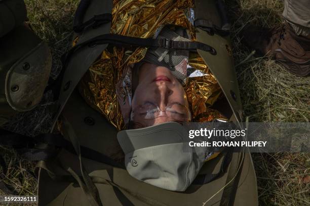 Woman lays on a stretcher while practicing fight first aid and evacuation during her 5-days of National resistance military training for civilians,...