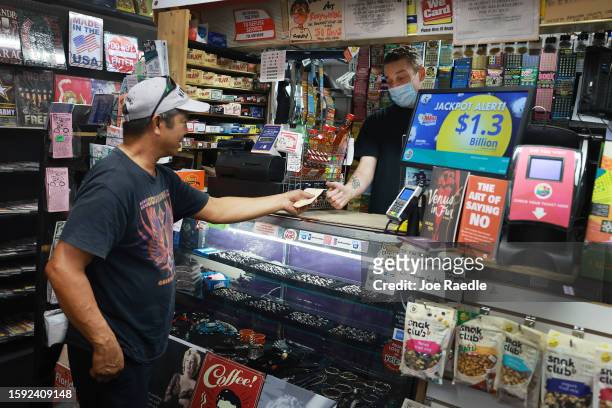 Erin Steinberg sells a Mega Millions lottery ticket to Joseph Francisco at his Bob's News & Books store on August 04, 2023 in Fort Lauderdale,...
