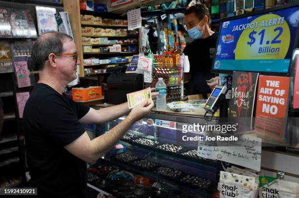 Erin Steinberg sells a Mega Millions lottery ticket to Anthony Bermude at his Bob's News & Books store on August 04, 2023 in Fort Lauderdale,...