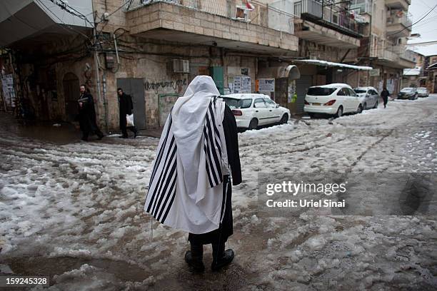 An Ultra-orthodox Jewish man wears a praying shawl in the snow in the Mea Shearim religious neighborhood on January 10, 2013 in Jerusalem, Israel.Ê