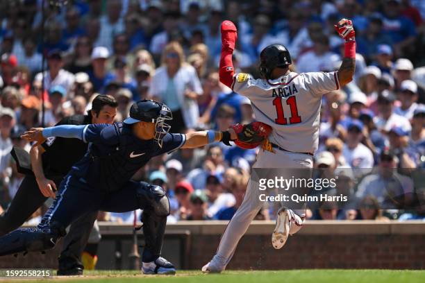 Orlando Arcia of the Atlanta Braves beats the tag from Miguel Amaya of the Chicago Cubs to score in the fourth inning at Wrigley Field on August 04,...