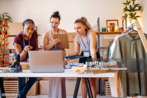 jeune femme utilisant un ordinateur portable dans sa petite entreprise - industrie de la mode photos et images de collection