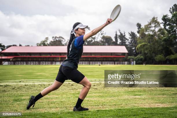 young woman throwing frisbee puck at the public park - throwing frisbee stock pictures, royalty-free photos & images