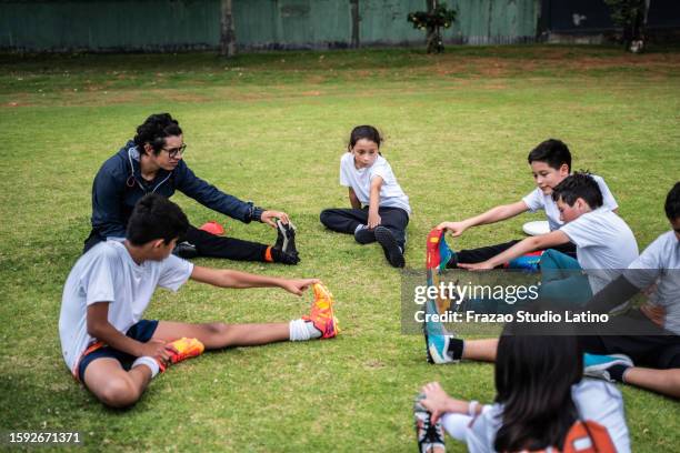 coach and children's team stretching before training on the sports field - physical education stock pictures, royalty-free photos & images
