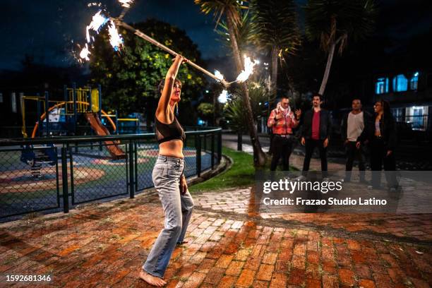mid adult fire juggler woman performing using flaming torch at night outdoors - fire performer stock pictures, royalty-free photos & images