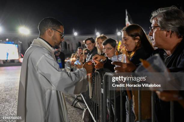 Priest helps participants to light candles as pilgrims and members of the faithful participate in the Rosary and the Candles Procession at the...