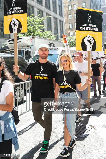 Stephen Amell and Cassandra Jean are seen walking the picket line with members of SAG-AFTRA in Downtown, Manhattan on August 11, 2023 in New York...