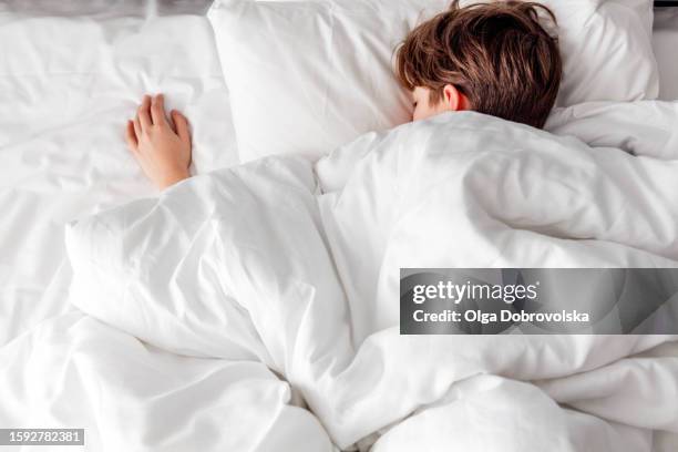 a sound asleep boy lying on a bed - pre adolescent child stock pictures, royalty-free photos & images