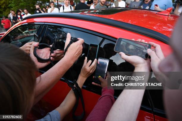 Bayern Munich fans take photos as the car with Tottenham Hotspur's English striker Harry Kane arrives at the Brothers of Charity Hospital in Munich,...