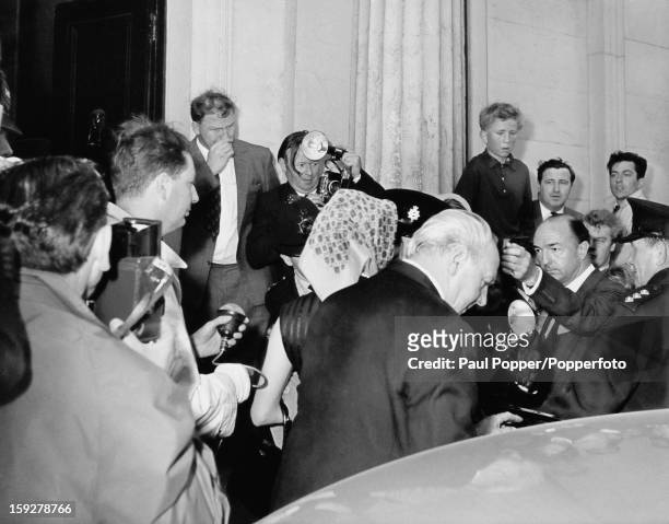 Former British Secretary of State for War John Profumo and his wife, Valerie Hobson are surrounded by photographers as they arrive at their home,...