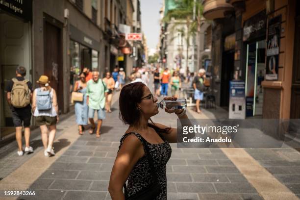 Woman drinks water from a bottle on a central street during a heat wave in the city of Santa Cruz de Tenerife, Canary Islands, Spain on August 11,...