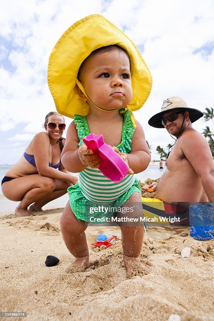 A family playing on the beach with their baby