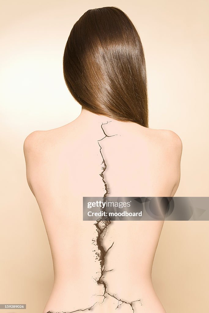 Bare back of woman with a crack on spine over colored background