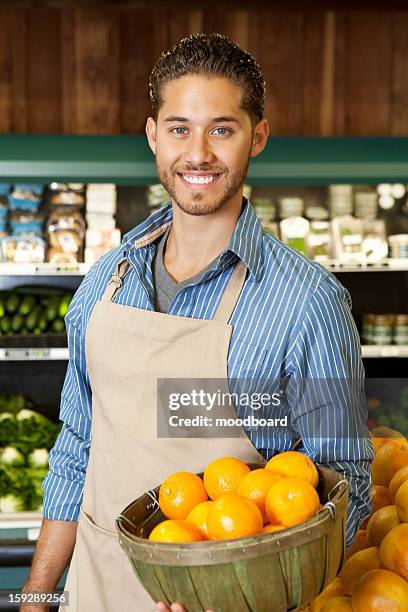 portrait of a happy salesperson with basket full of oranges in market - oranges in basket at food market stock pictures, royalty-free photos & images