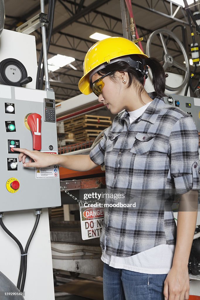 Female industrial worker operating manufacturing machine at factory