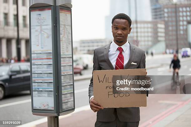 young businessman holding ""will work for food"" sign at street - poor africans stock pictures, royalty-free photos & images