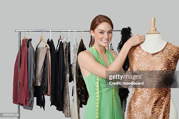 portrait of beautiful female fashion designer adjusting cloth on tailor's dummy - mannekin pis photos et images de collection