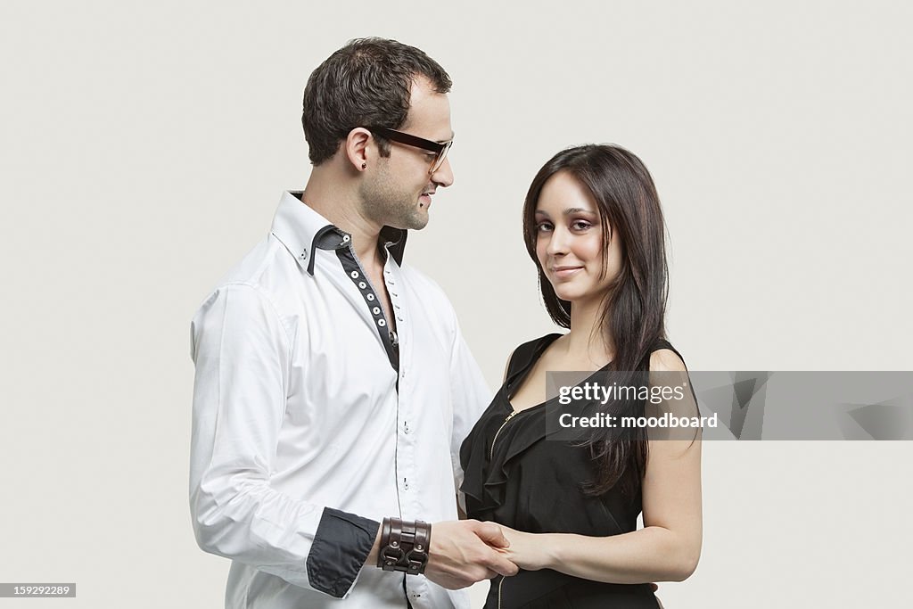 Young couple holding hands against gray background