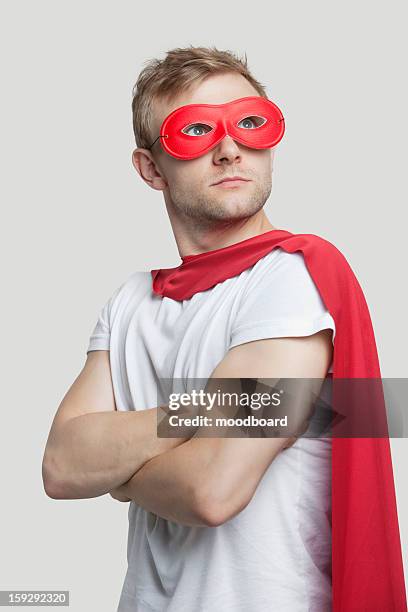 young man in red superhero costume looking up over gray background - cape garment stock pictures, royalty-free photos & images