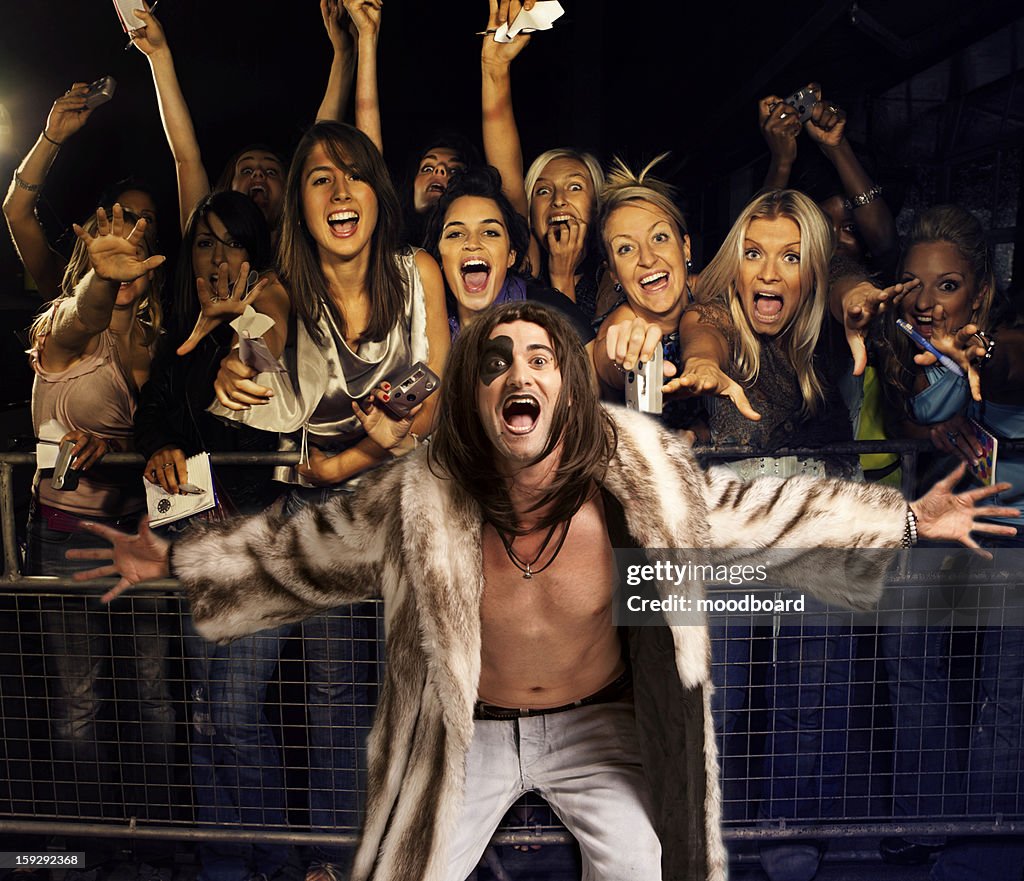 Portrait of young man in fur coat screaming with excited audience in the background