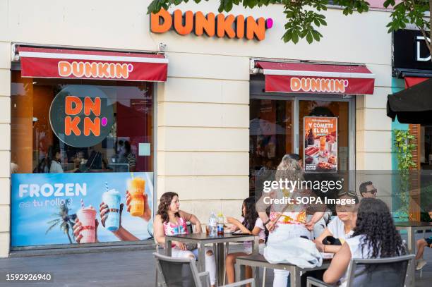 Customers are seen eating at the American multinational coffee and snack chain Dunkin' Donuts in Spain.